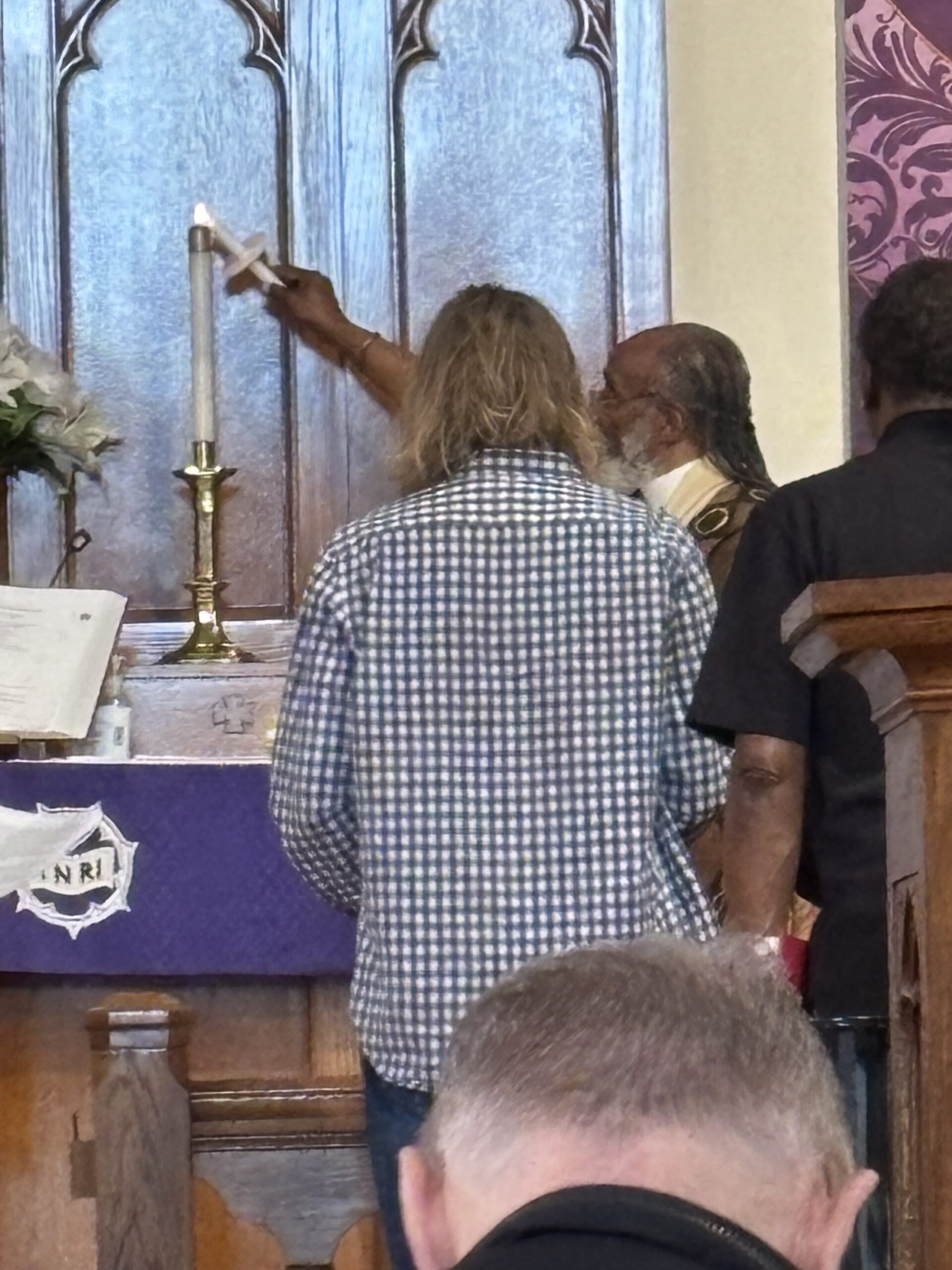 Pastor Starr lights a candle at the altar during baptism rite.